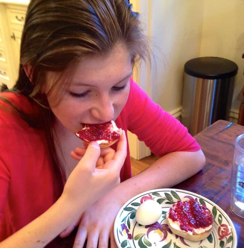 teen eating a bagel with jam